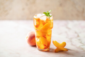 Peaches iced tea  in a glass on the table. Summer drink concept