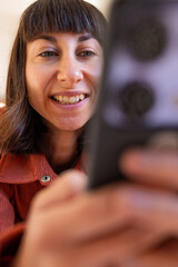 woman using mobile phone relaxing on sofa at home. Happy lady sitting on the sofa and looking at the smartphone, holding a mobile phone and sending text messages.