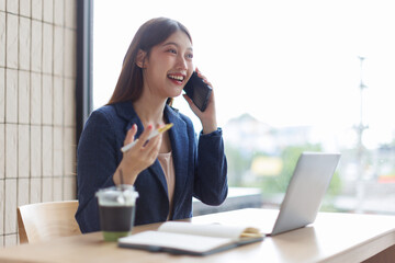Young Asian businesswoman talking on the phone with her business partner, dealing or negotiating...