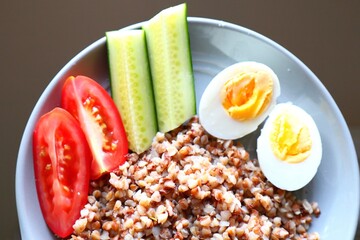 Buckwheat with boiled egg, cucumbers and tomatoes, breakfast