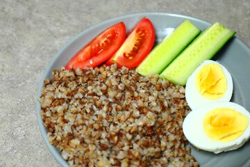 Buckwheat with boiled egg, cucumbers and tomatoes, breakfast