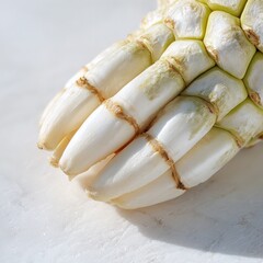 A close up of a bundle of white vegetables with brown rings on a white surface in bright light
