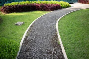 Walkway and landscape in garden, park. Also called path, footpath, pathway or asphalt floor. Include pit cover, natural plant, bush, lawn and grass. Landscaping decoration of outdoor.