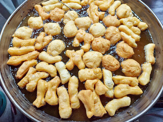 Youtiao (Chinese fried dough) frying in a large pan.