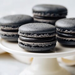 Close up of several dark gray macarons stacked on a white pedestal cake stand dessert food photography