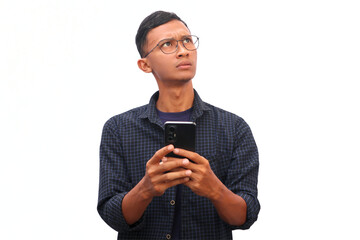 An Asian man holds a cellphone with a thinking expression.