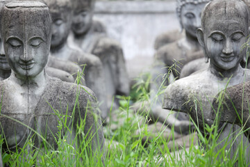 Obraz premium Ancient Stone Statues of Buddha Surrounded by Green Grass