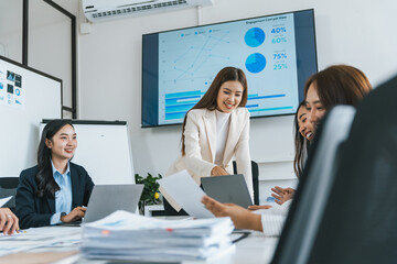 Business team analyzing financial charts and graphs, working with documents and using laptop during a productive meeting in modern office