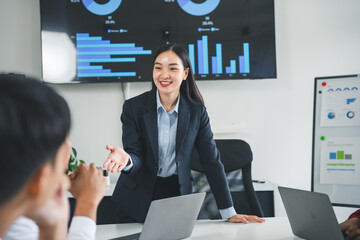Asian businesswoman leading a meeting and presenting financial chart on the monitor in the meeting room