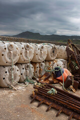 Old rusty scallop dragging and lobster pots trapscommercial fishing equipment at a fishing harbour dock.