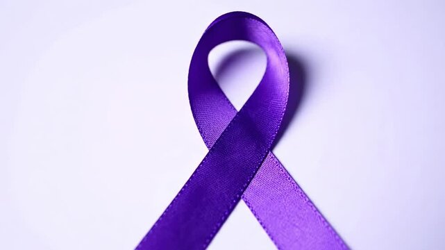A single purple awareness ribbon lies on a light purple backdrop