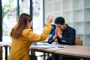 Angry businesswoman arguing with businessman during tense office meeting, highlighting conflict and...