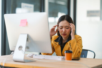 Young manager suffering from headache while working on computer at workplace, concept of work...