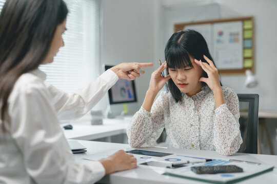 Asian businesswomen are stressed and having a headache with bad work results, manager blaming employee for mistakes in office