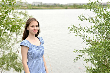 Smiling young woman in blue top looking at the camera outdoors on a blurred city background.