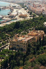 Historic architecture amidst lush greenery with a port city backdrop.