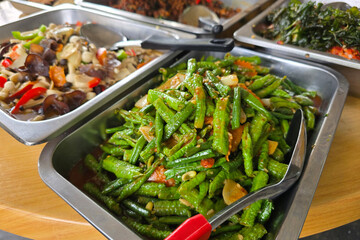 A flavorful tray of stir-fried long beans mixed with red chili and onions, part of a local mixed rice spread.