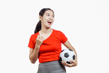 Confident young Asian woman in vibrant red shirt stands against white background, cheering joyfully...