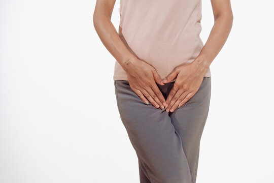 Confident young Asian woman in light brown shirt stands against a white background, experiencing vaginal pain. inflammation, cysts, endometriosis gynecological conditions affecting female health.