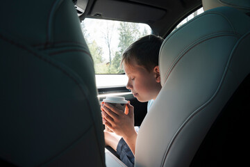 boy drinking a take away hot chocolate in a car