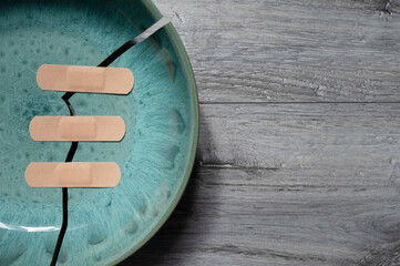 Cracked ceramic plate with band-aids.