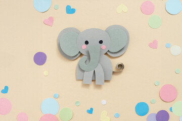 Playful elephant made of grey and green paper with pink cheeks, surrounded by colorful paper hearts and circles. Perfect for children crafts, DIY kits, or educational materials.