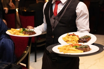 Waiter serving plates of food in restaurant