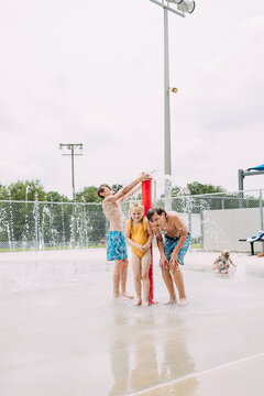 Big kids playing at splash pad in water fountain in summertime