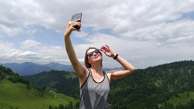 A woman takes a selfie at the Alpine views in Tyrol