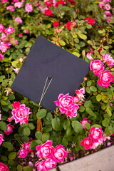 a graduation cap with a gold tassel in a bed of pink roses