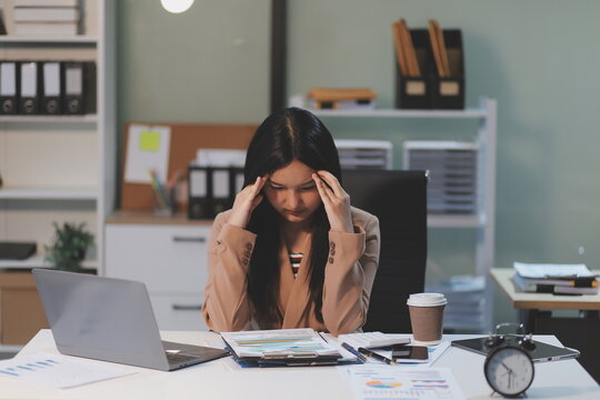 Asian women are stressed while working on laptop, Tired asian businesswoman with headache at office, feeling sick at work, copy space - Powered by Adobe