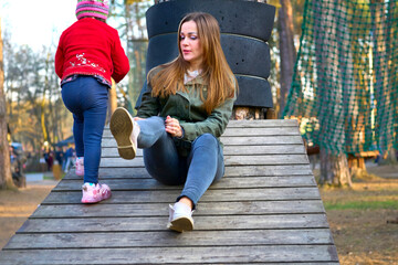 Young attractive mother adjusting jeans while walking with her daughter