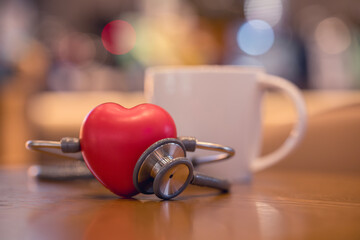 Red heart shape exercise ball with doctor physician's stethoscope on coffee shop background, Heart disease and coffee drinking concept, world heart health day. doctor day.