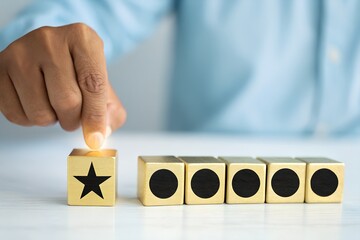 Hand placing gold star block, ranking, rating