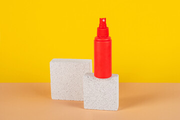 Cosmetic red bottle. Womens cosmetic accessory for makeup with stylish props on yellow background.