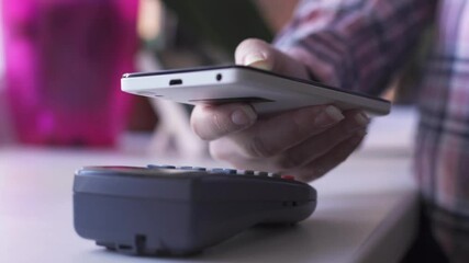 Person making contactless payment with a smartphone over a card reader. - Powered by Adobe