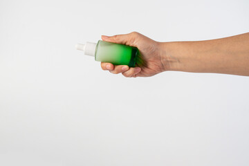 Green glass cosmetic bottle, Skin care or sunscreen cosmetic with hand on white background.