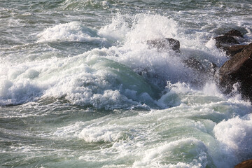 The ocean is rough and the waves are crashing against the rocks