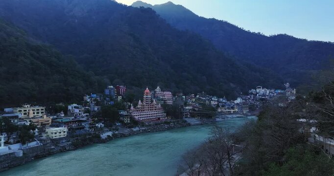 Drone shot of Rishikesh City. Aerial view of the beautiful holy river Ganga, Lakshman Jhula bridge, and Tera Manzil Temple, Trimbakeshwar in Rishikesh. A sacred town and travel destination in India.