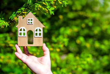 A girl holds the symbol of a house against a blooming acacia tree
