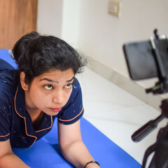 Young Indian woman practicing yoga indoor by online yoga session, Beautiful girl practice basic yoga pose, Asian Indian lady doing indoor yoga