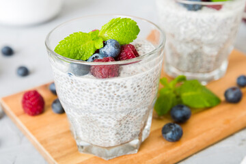 Healthy breakfast or morning with chia seeds vanilla pudding raspberry and blueberry berries on table background, vegetarian food, diet and health concept. Chia pudding with raspberry and blueberry