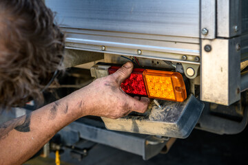 A mechanic repairs a tail light on a ute truck.