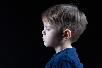 Headshot Portrait of Little Caucasian Kid Profile With Sad Negative Expression Over Black Background