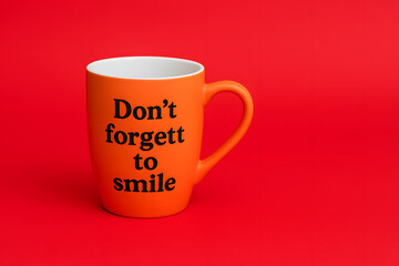 Orange Mug with 'Don't Forget to Smile' on a Red Backdrop, Motivational Drinkware Design for Uplifting Mornings