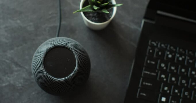 HomePod Mini speaker with assistant to play music, static on desk. Concept of a smart home.