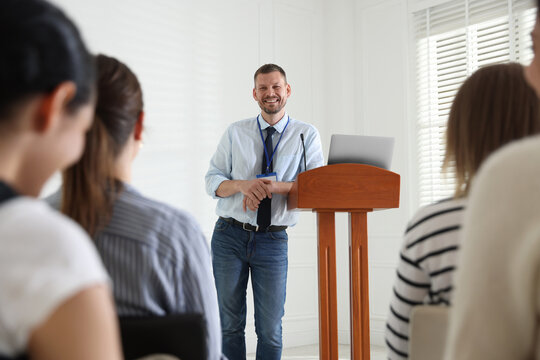 Man giving public speech at lectern in front of audience indoors