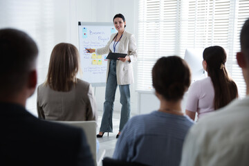 Woman giving public speech in front of audience indoors