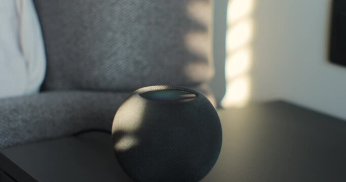 Smart speaker turning on, reacting to voice activation. Alarm clock working on smart portable device. Turning off the alarm clock. Concept of a smart home.