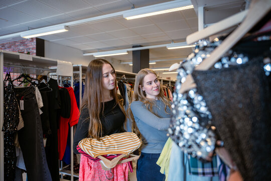 Two young women browsing clothes at second hand clothing store